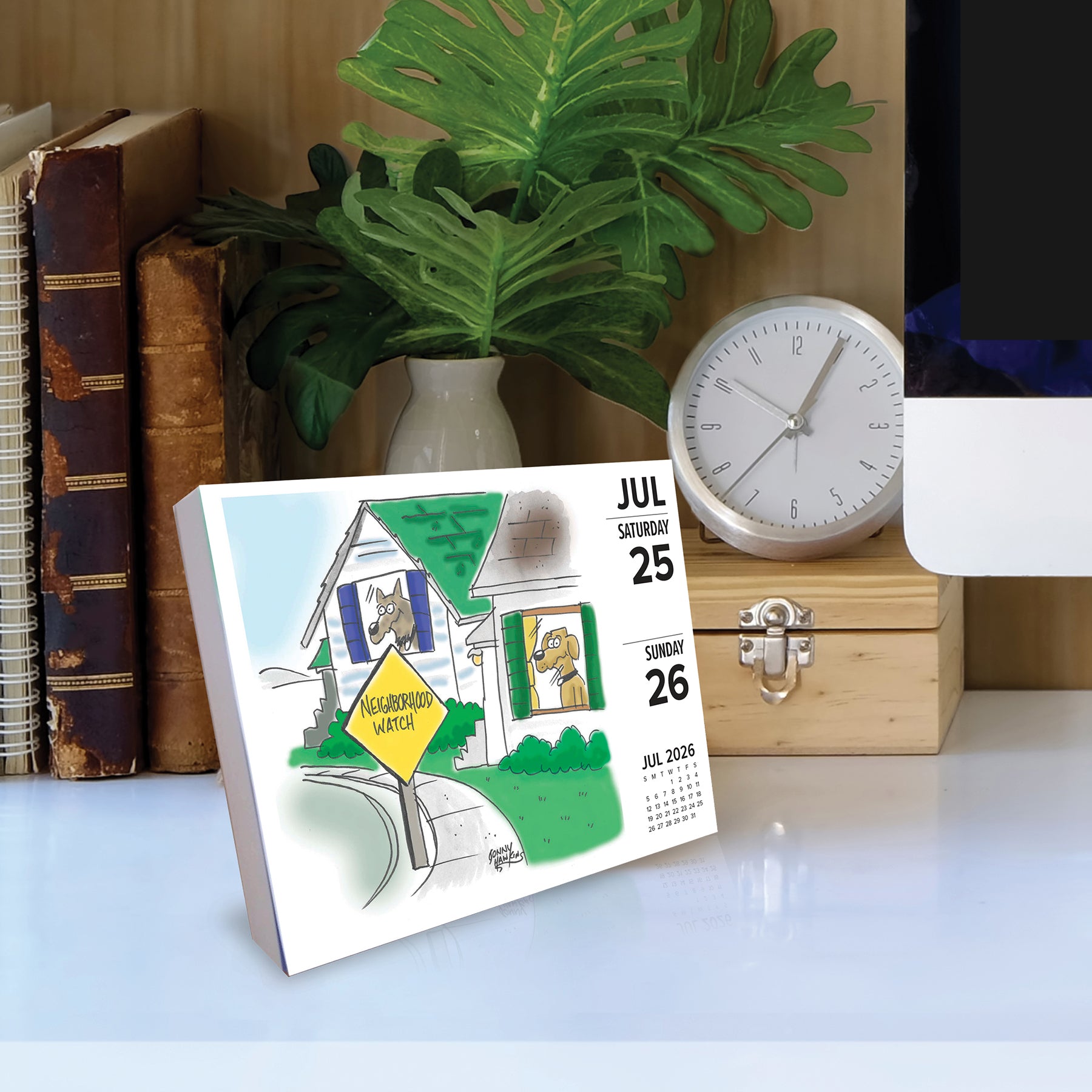 Dog Cartoon-A-Day 2026 Daily Box Calendar displayed on a desk with a clock and books, featuring a humorous dog illustration.
