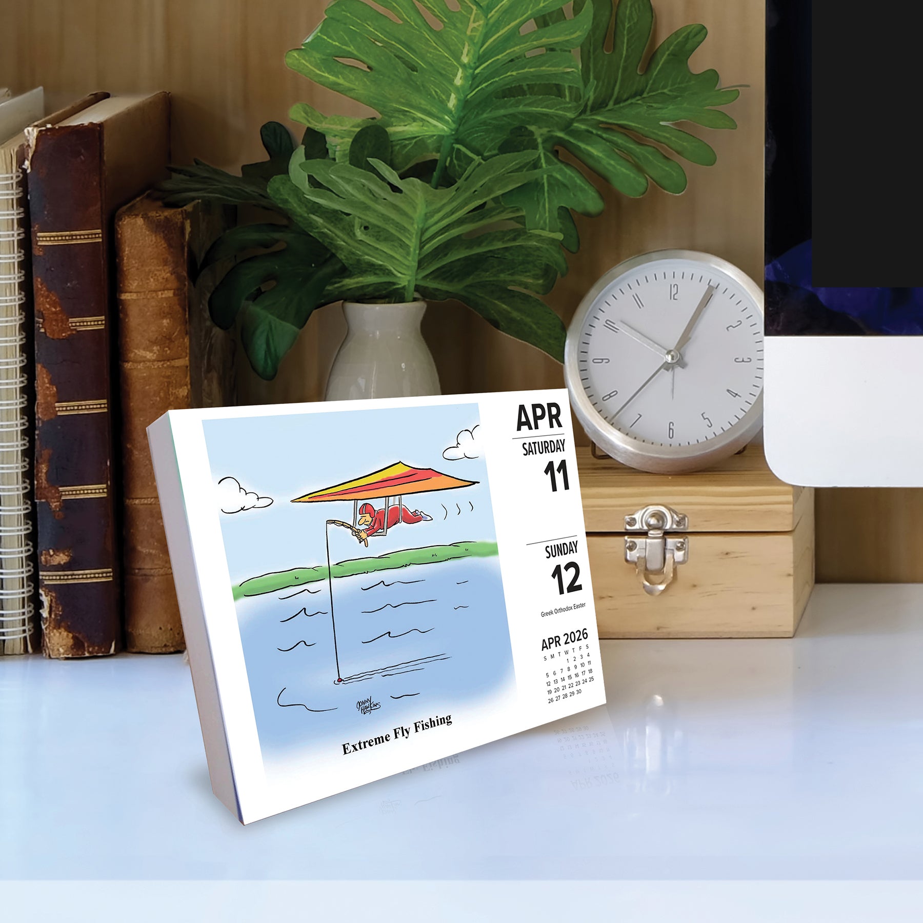 Fishing Cartoon-A-Day 2026 Daily Box Calendar featuring extreme fly fishing illustration on display.