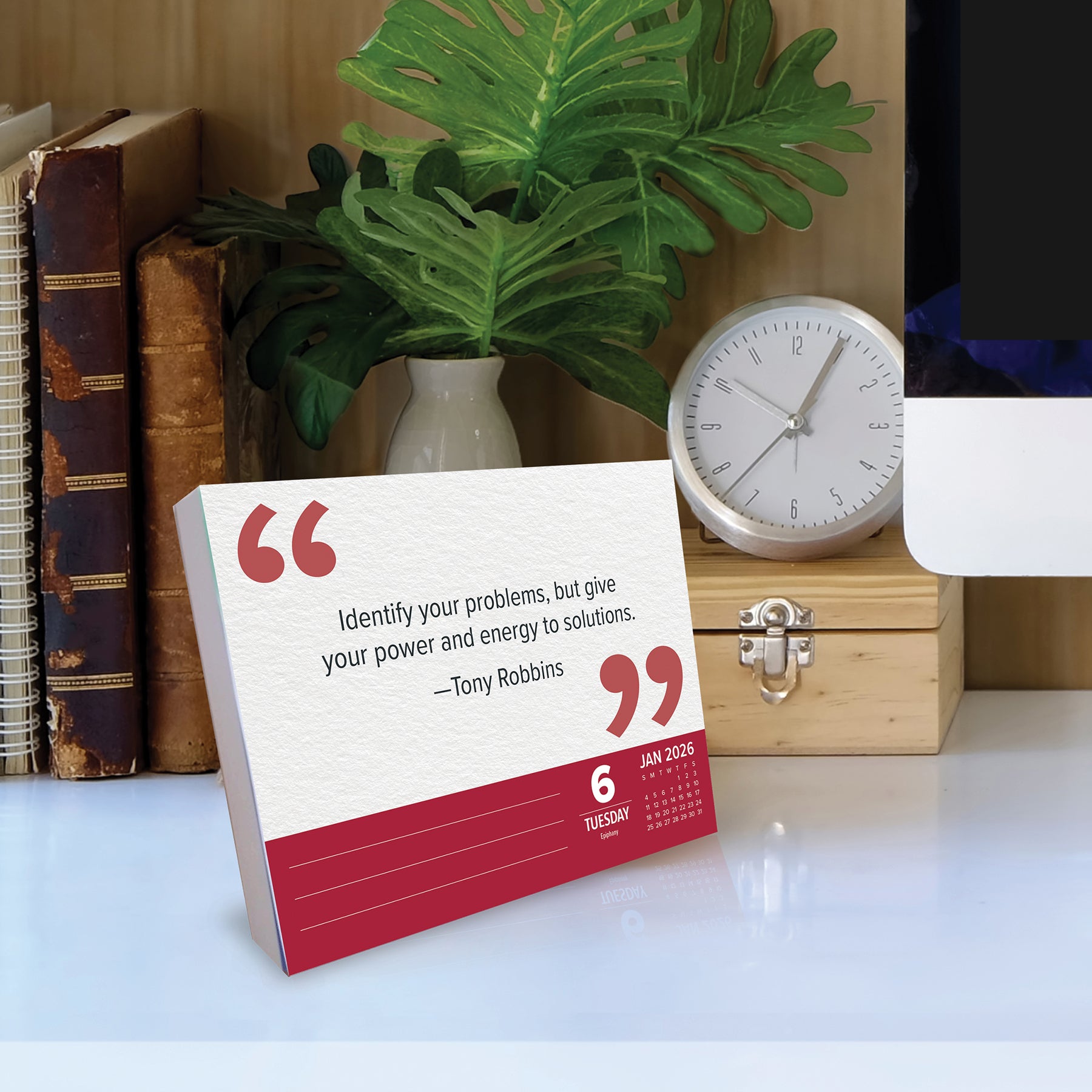 2026 Daily Box Calendar featuring a quote by Tony Robbins on a desk with plants and a clock.