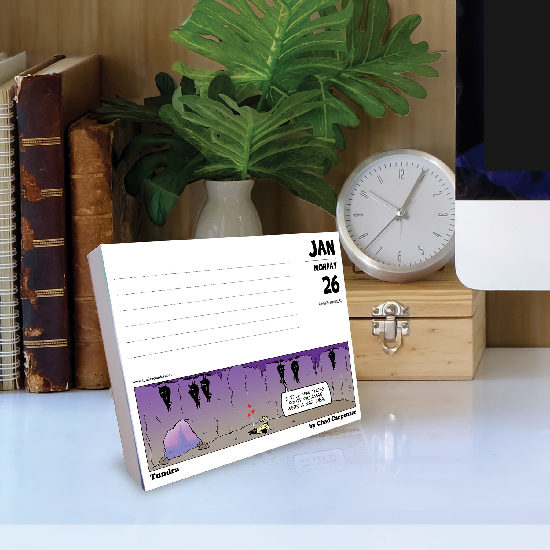 Tundra 2026 Daily Box Calendar displaying January 26 comic on desk with clock and plants.